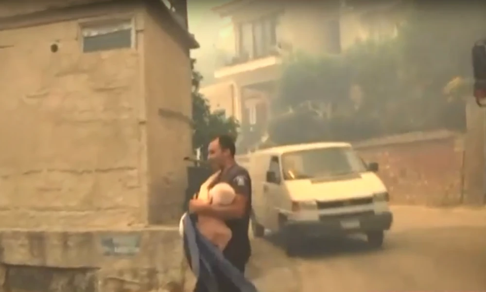 Πάτρα: Αστυνομικός παίρνει στα χέρια ηλικιωμένο για να τον απομακρύνει από τη φωτιά